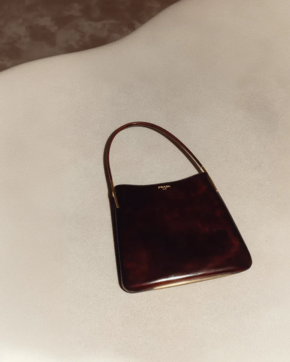 AI-generated burgundy handbag still life visual created by Officine AI